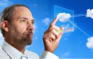 A business man touches a cloud on a computer display. He may be interested in these cloud computing stocks to buy now.