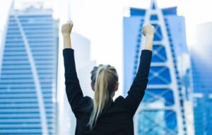 A business woman celebrating in front of a skyline after learning how to achieve financial freedom in 5 years