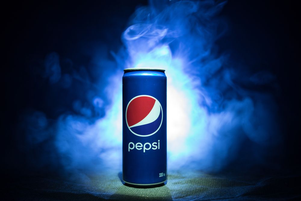 A blue can of Pepsi against a beautiful hazy and cloudy black and blue background | Investment U